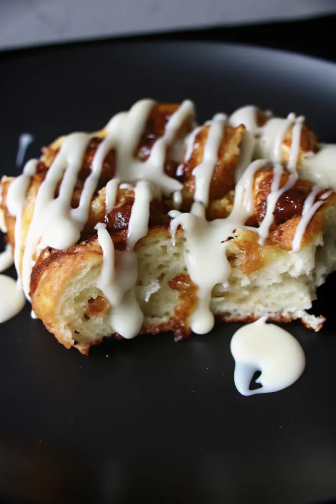 Sourdough cinnamon roll focaccia slice drizzled with cream cheese glaze