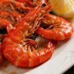 Golden-brown Fried Argentine Red Shrimp Recipe on a white plate, garnished with lemon wedge and parsley, crispy, succulent, and ready to serve.