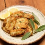 Artichoke Francese on a rustic plate with lemon wedges and sage.