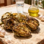 Grilled Spanish artichokes on rustic table with olive oil and garlic