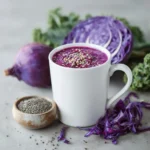 21-Day Cleanse purple peel weight loss blend in white mug topped with chia and sesame seeds, surrounded by halved red cabbage, whole purple cabbage and bowl of chia seeds on grey surface