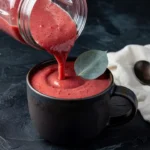Pouring a thick and creamy strawberry Keto Smoothie for Weight Loss into a dark ceramic mug