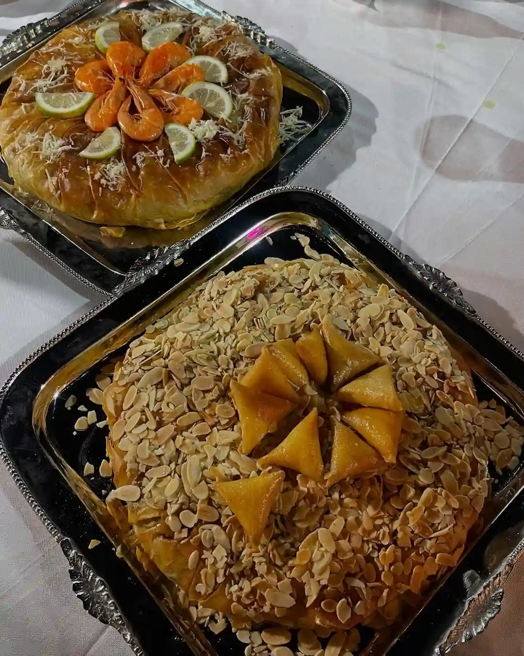 Homemade bastilla with seafood and almond topping served on trays, a signature recipe by Emily.