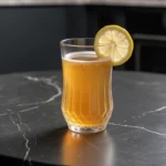 A clear glass of the Serena Williams gelatin trick recipe with a lemon garnish on a black surface.