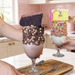 Cake shaker recipe: two elaborate layered desserts in stemmed glasses with cake cubes, frosting, sprinkles, and chocolate chips.