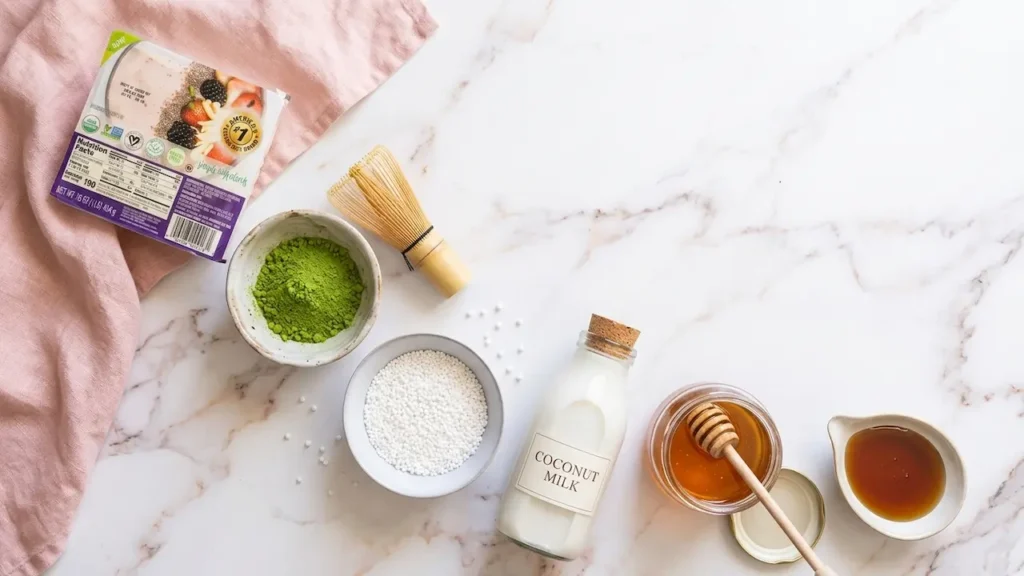 Matcha Taho Recipe: 4 Easy Steps to Green Tea Filipino Twist 11 Matcha taho ingredients flat lay: silken tofu, matcha powder, bamboo whisk, tapioca pearls, coconut milk, and honey on marble.